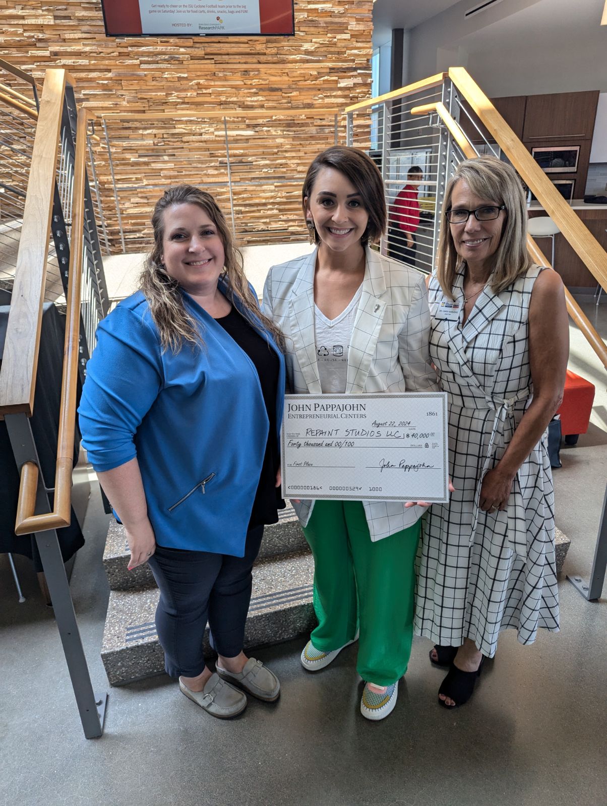 Pappajohn Center staff and entrepreneur holding a large award check.