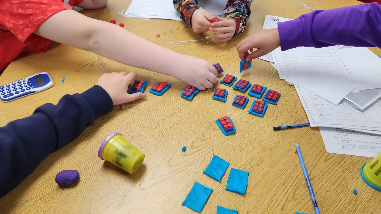 Children collaboratively making fake prototypes out of Play-Doh