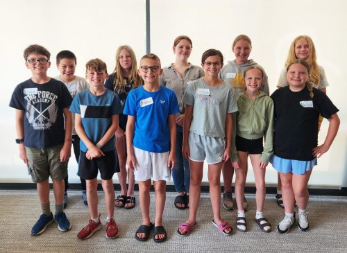 A group of eleven middle school students standing and smiling at the camera.
